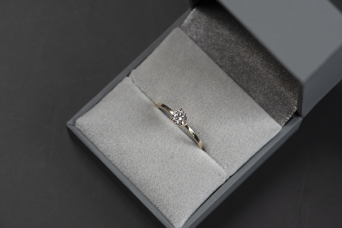 Prosty złoty pierścionek zaręczynowy z naturalnym lub laboratoryjnym 0,3 ct w szarym pudełku na biżuterię