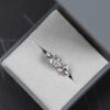 Pierścionek z białego złota próby 585 z diamentem laboratoryjnym 0,4 ct, sybtetycznymi moissanitami markizami i okrągłymi różowymi diamentami. Pierścionek zaręczynowy umieszczony w szarym pudełku na biżuterię.