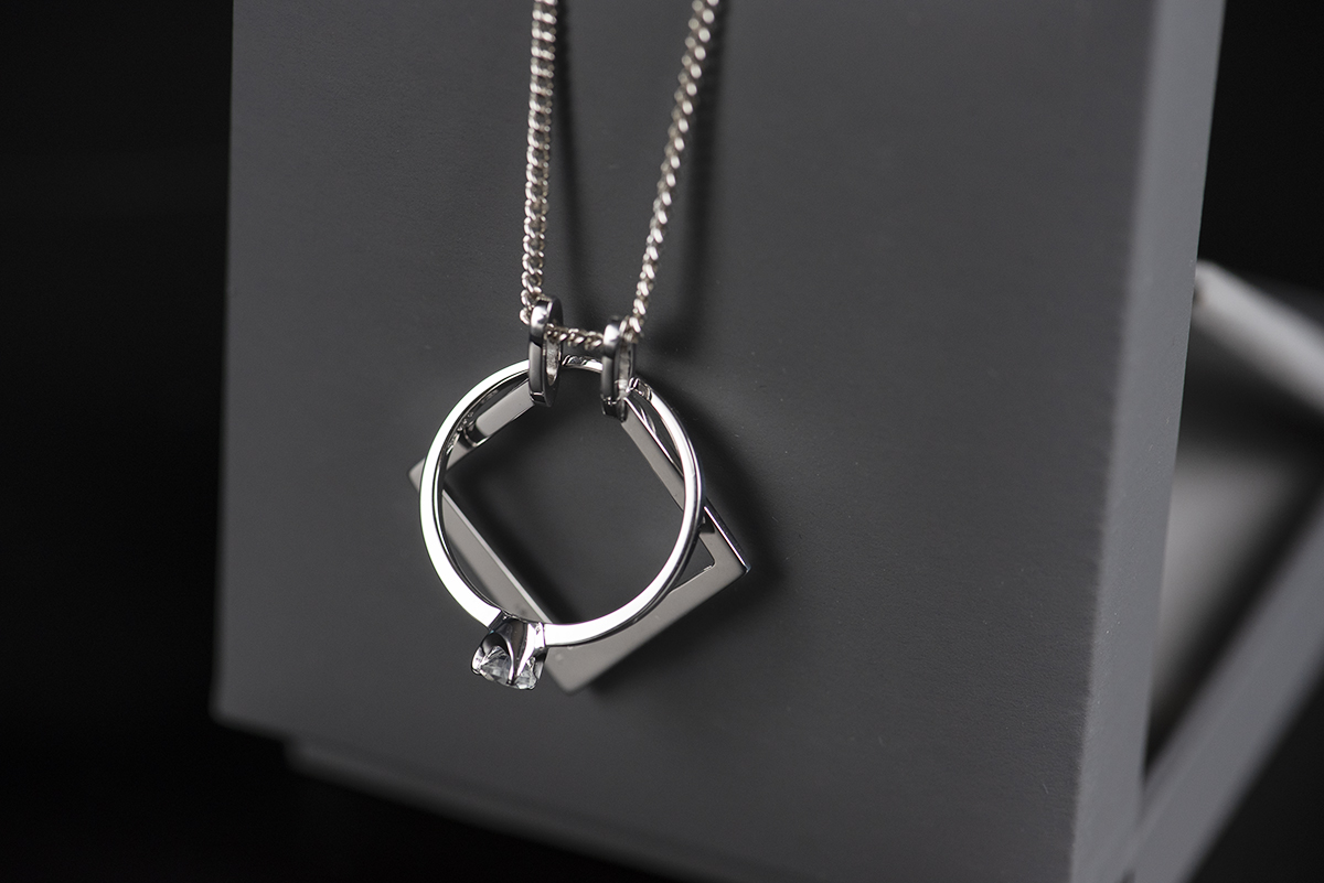 Ring holder wykonany z białego złota próby 585. Zawieszka na którą można założyć pierścionek bez konieczności rozpinania łańcuszka. Umieszczony w szarym pudełku na biżuterię. Łańcuszek przewieszony przez wieczko pudełka na biżuterię. Na zawieszce wisi pierścionek z białego złota z kamieniem księżycowym.